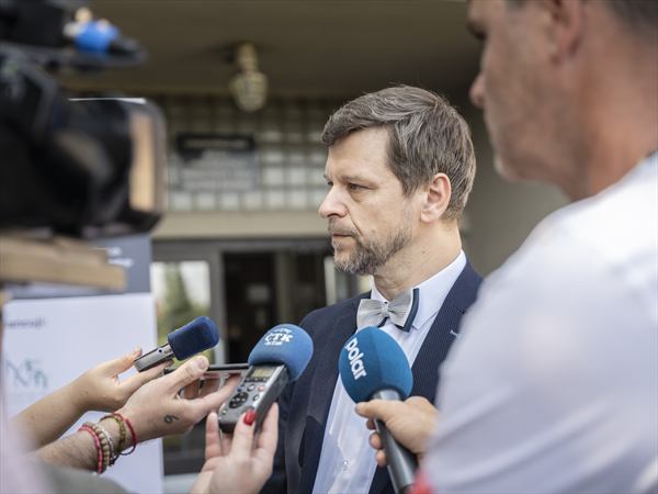 Petr Kopecký odpovídá novinářům před univerzitní budovou, v popředí mikrofony ČTK a POLAR.