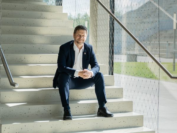 Petr Kopecký sedí na schodech v prosklené univerzitní budově.