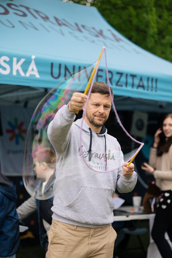 Petr Kopecký při neformální univerzitní akci vytváří velkou mýdlovou bublinu.
